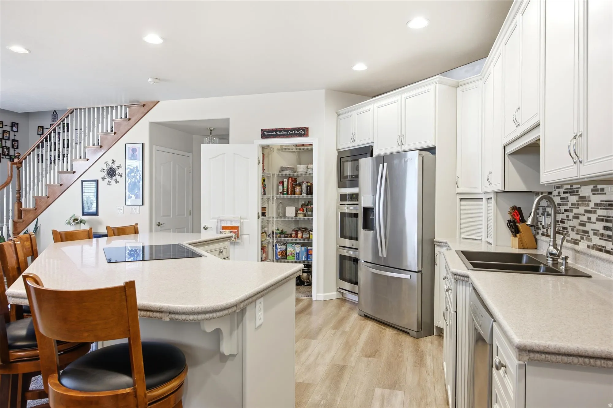 Well-appointed kitchen featuring light-toned countertops and a mosaic tile backsplash
