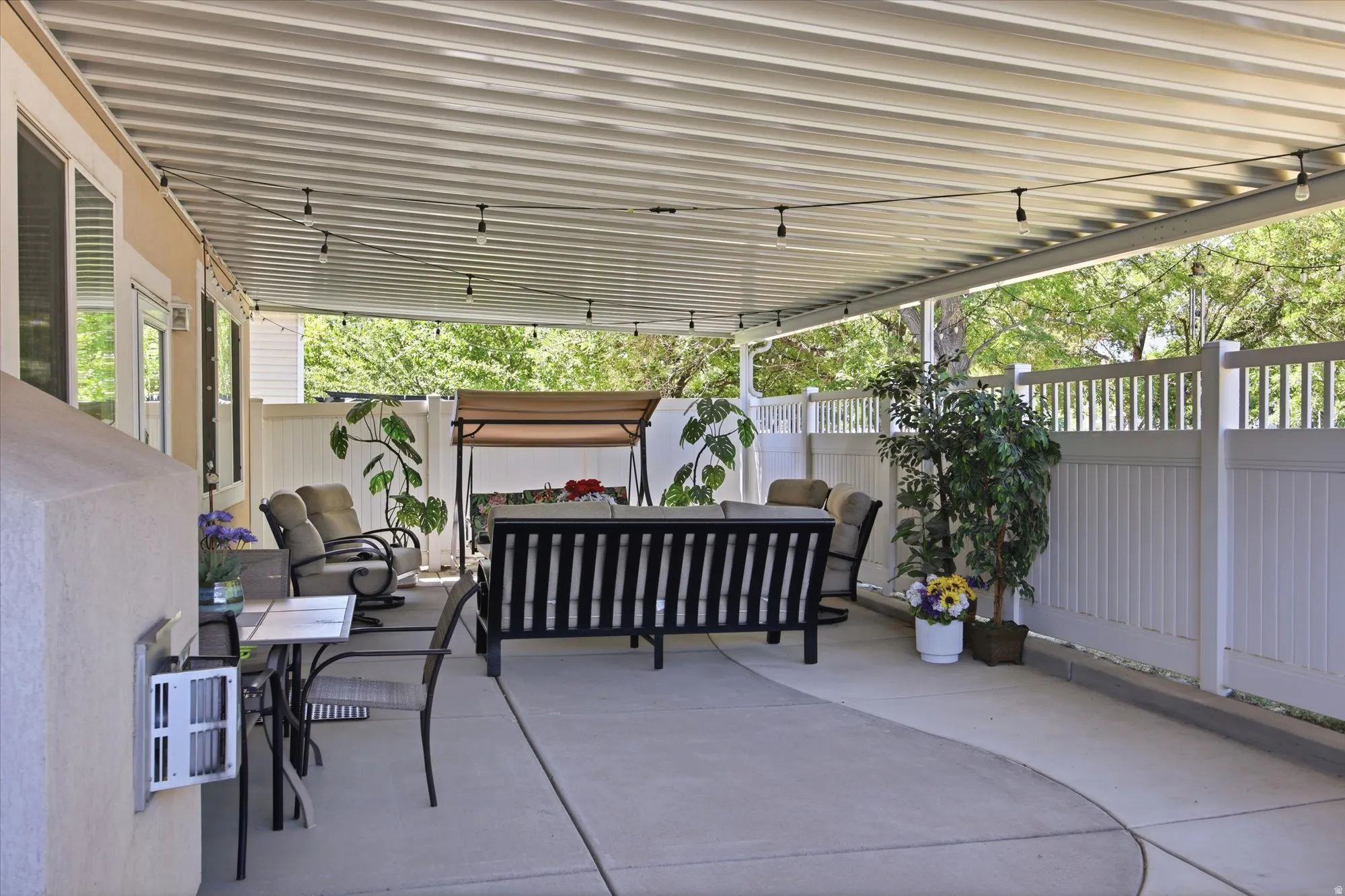 Expansive concrete patio with a full-coverage overhead awning and string lighting