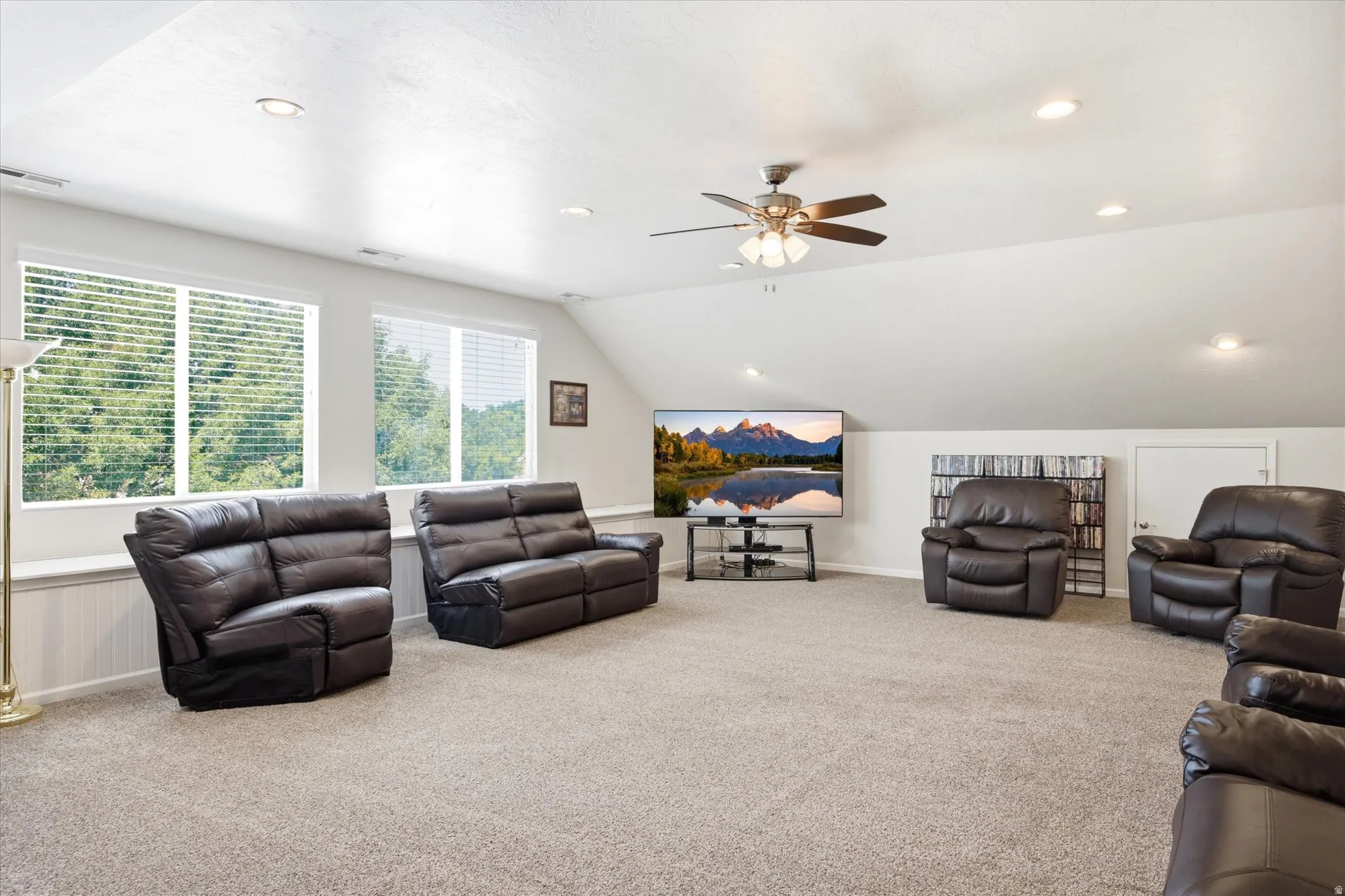Spacious room with a neutral carpet, multiple recessed lights, and a ceiling fan