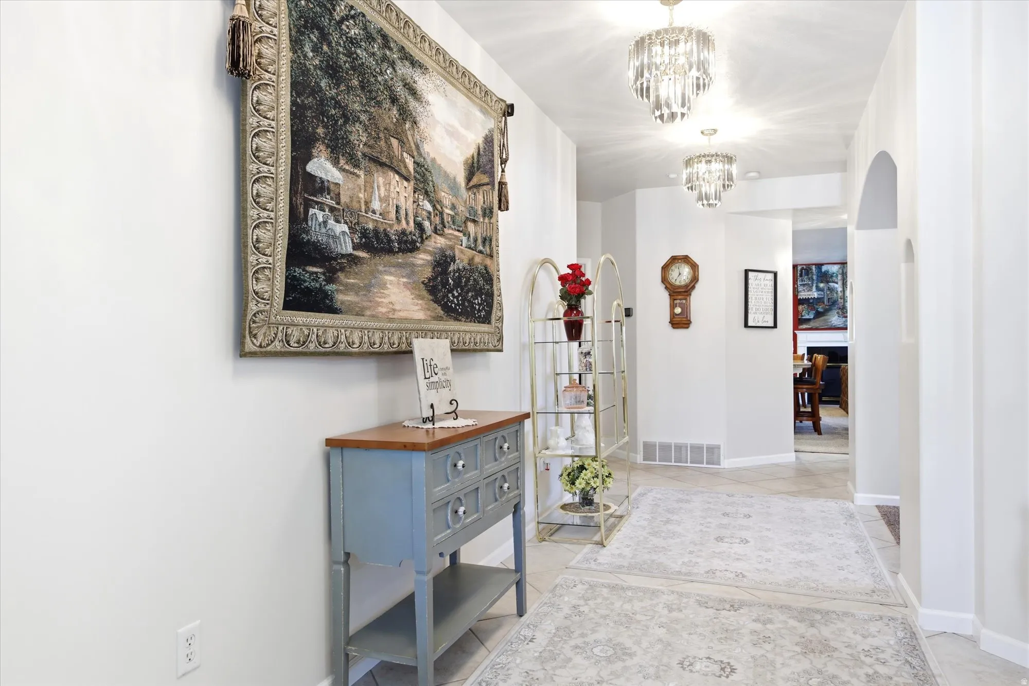Hallway featuring recessed lighting, two crystal-style chandeliers, arched doorways, and tile flooring
