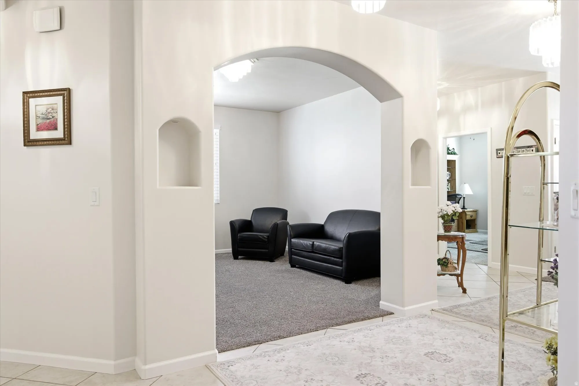 Archway entry featuring recessed wall niches, tile flooring, and carpeted interior