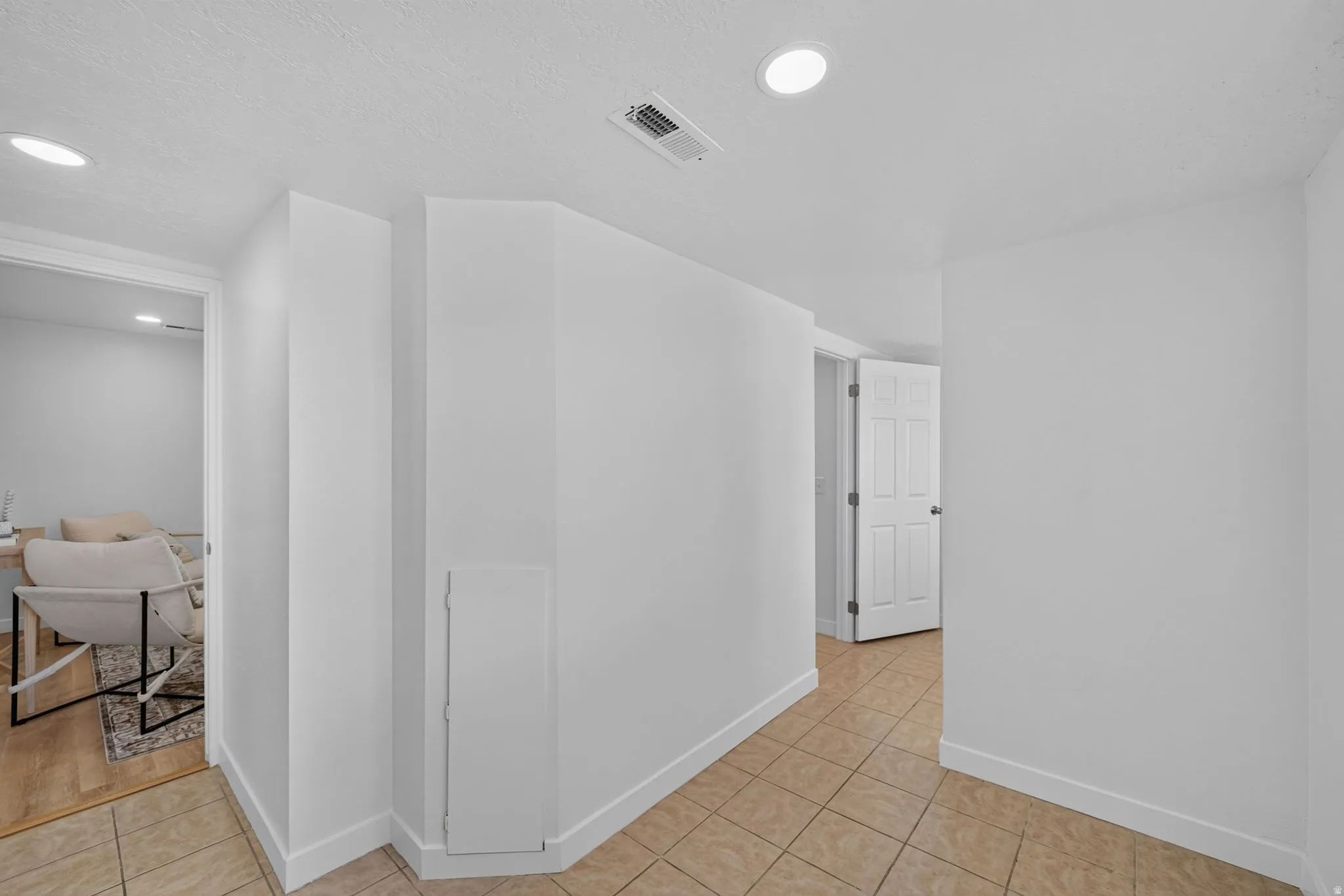 Tile flooring extending into a hallway with recessed lighting