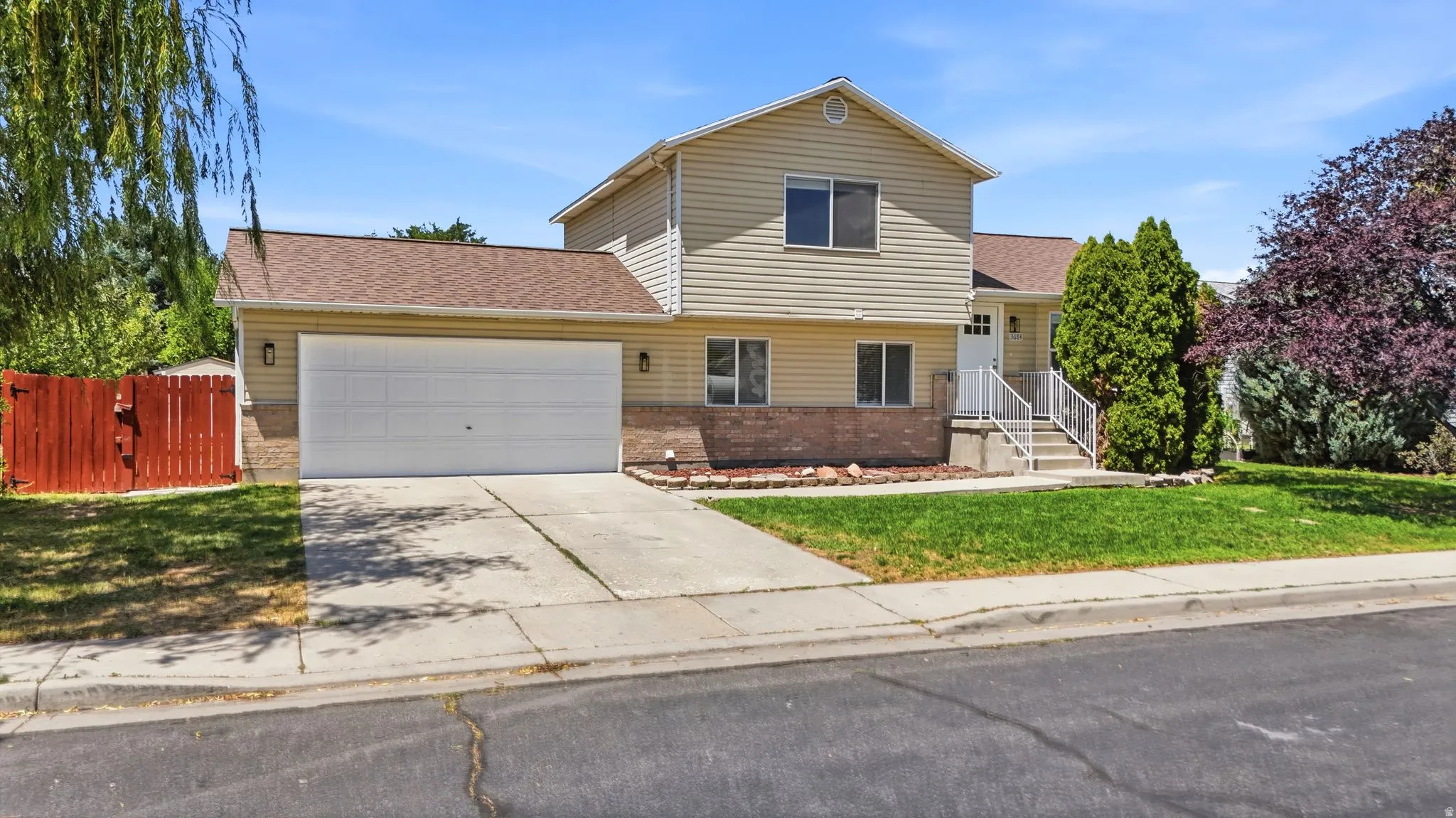 Two-story residence featuring light-colored siding, a two-car garage, and a concrete driveway