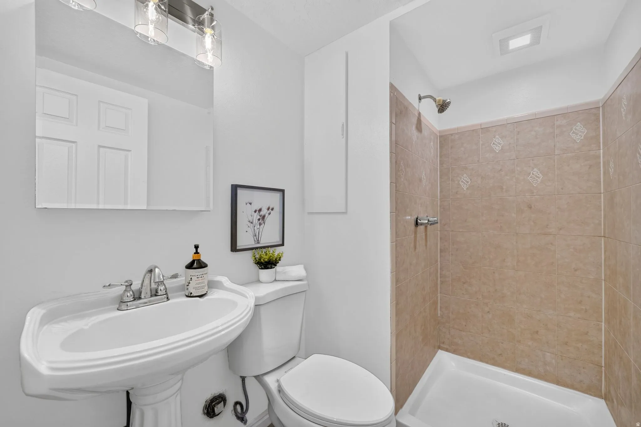 Bathroom featuring a pedestal sink, chrome faucet, and a shower with light brown wall tile