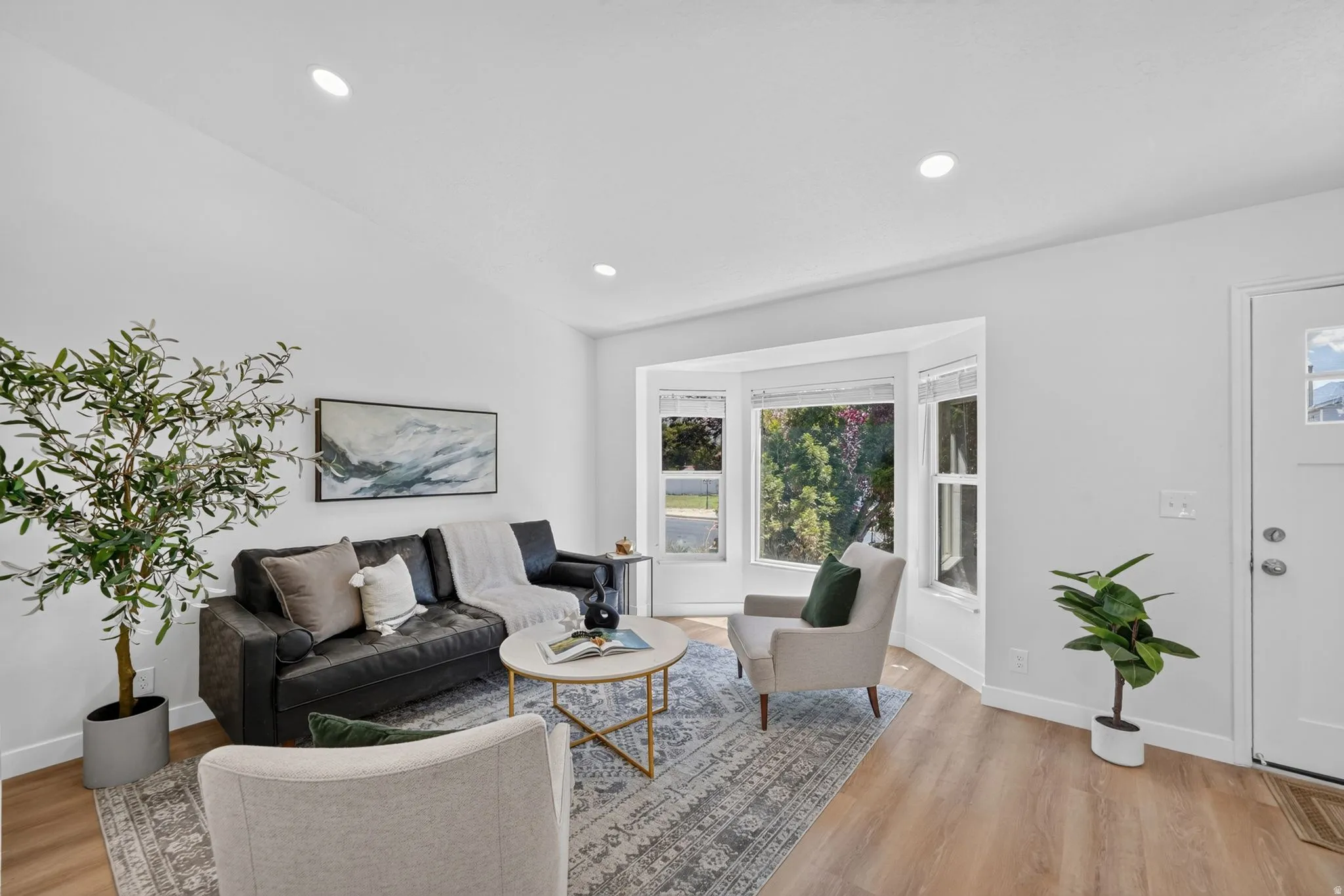 Bright living area featuring a bay window, recessed lighting, wood-finish flooring, and white baseboards