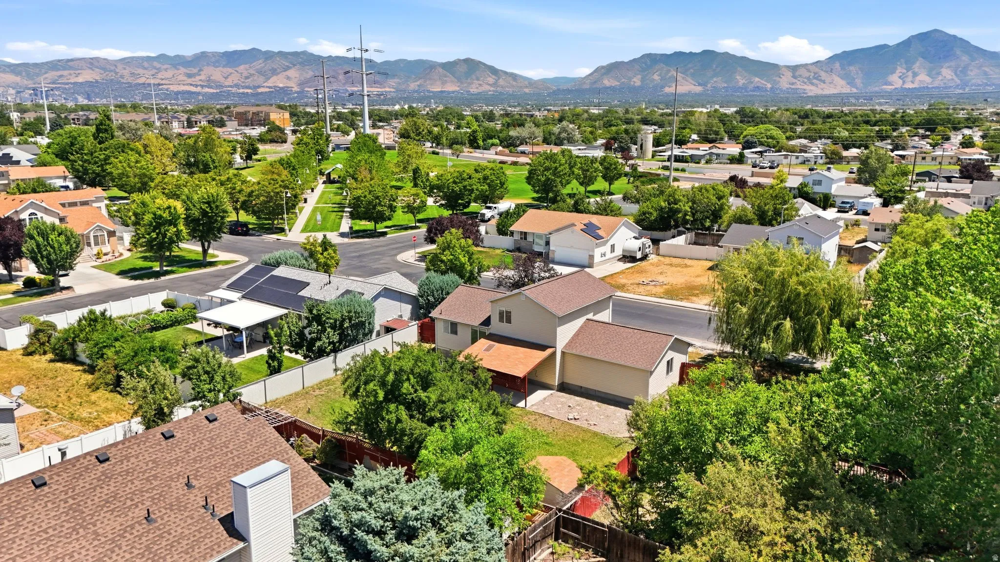 Suburban neighborhood featuring varied residential architecture, mature landscaping, and mountain backdrops