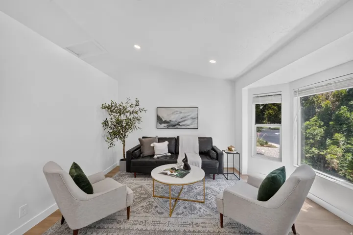 Bright living area featuring wood-finish flooring, recessed lighting, and a bay window