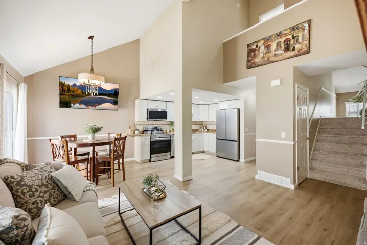 Vaulted ceilings enhance this open-concept living space with wood-finish flooring