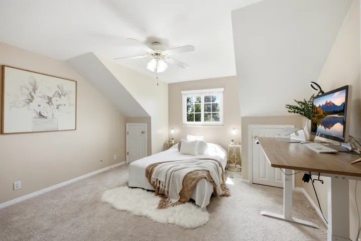 Primary bedroom featuring a ceiling fan, window with white blinds, and two paneled doors