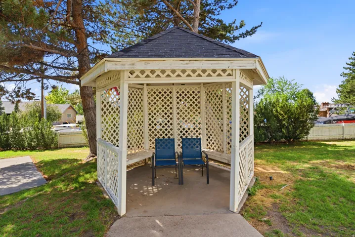 Hexagonal lattice gazebo with a shingled roof and concrete flooring