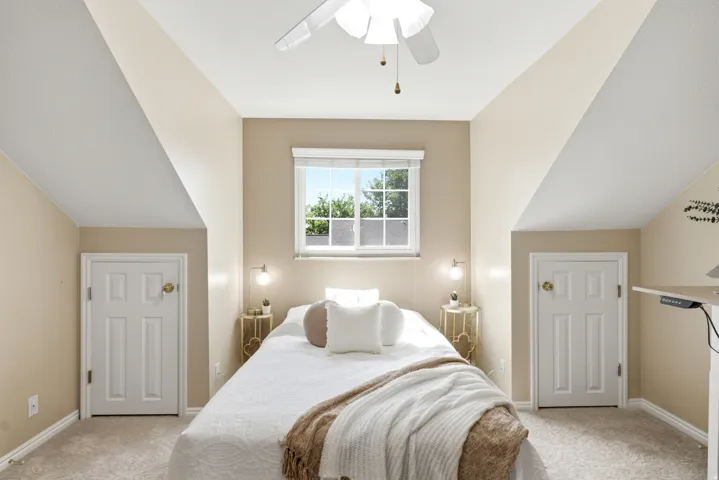 Primary bedroom with a window, ceiling fan, and sloped ceilings