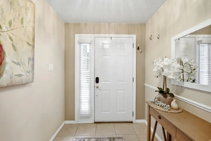 Entryway featuring a paneled door with hardware, sidelight with blinds, tile flooring, and wall-mounted coat hooks