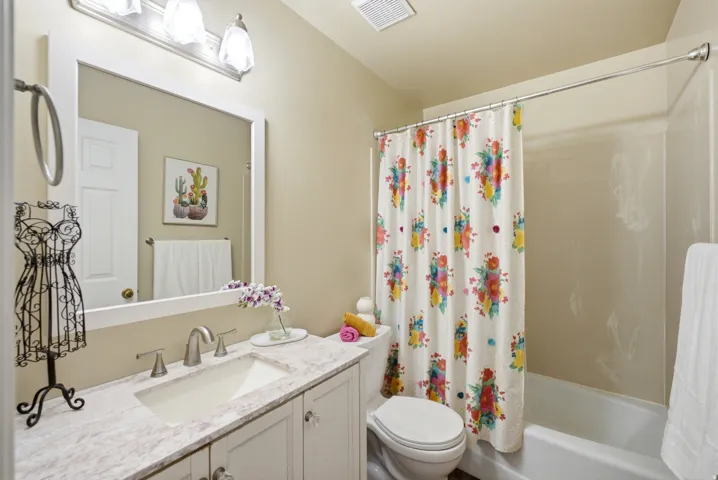 Bathroom featuring a single vanity with stone-finish countertop, under-mount sink, and brushed nickel fixtures