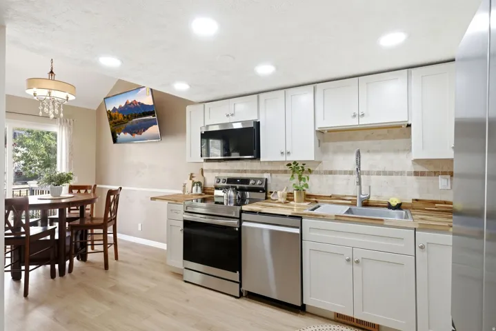 Kitchen featuring white cabinetry, light wood-finish countertops, stainless steel appliances, and a tiled backsplash