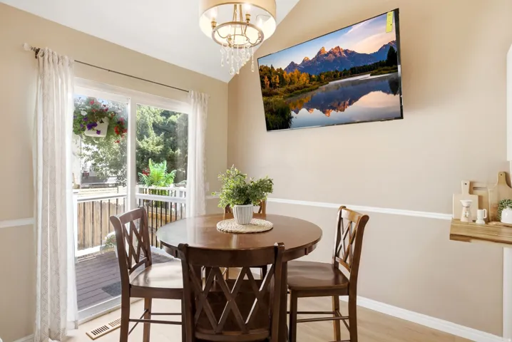 Dining area featuring wood-finish flooring, a contemporary chandelier, chair rail molding, and a sliding glass door providing outdoor access