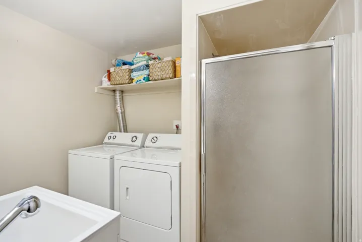 Dedicated laundry area featuring a white washer and dryer, an overhead storage shelf, and a utility sink with a chrome faucet
