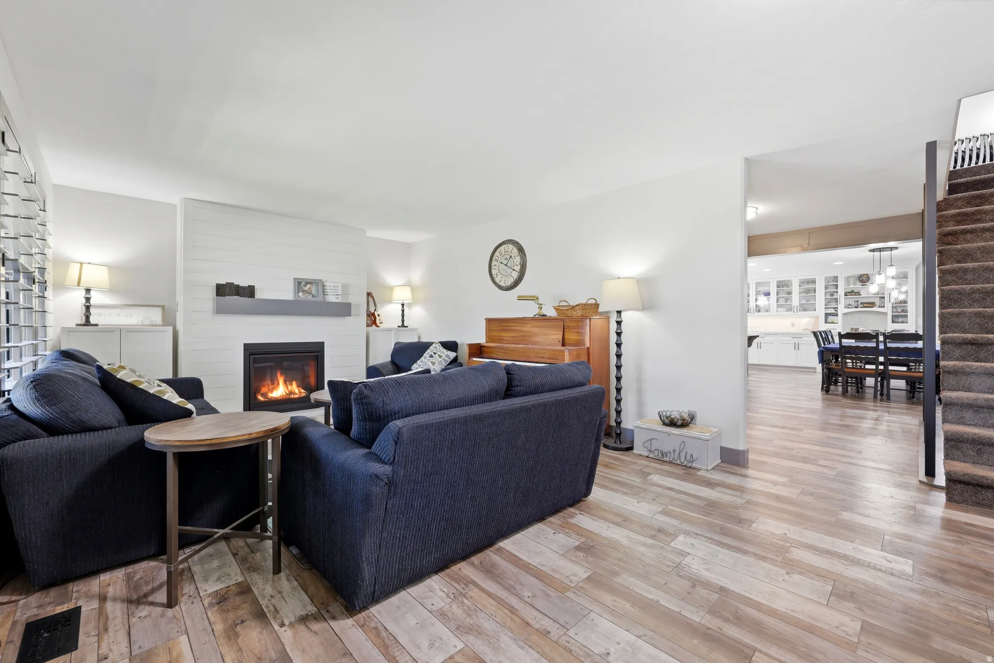 Living space with wood-finish flooring and a fireplace featuring a shiplap-style accent wall and a gray mantel