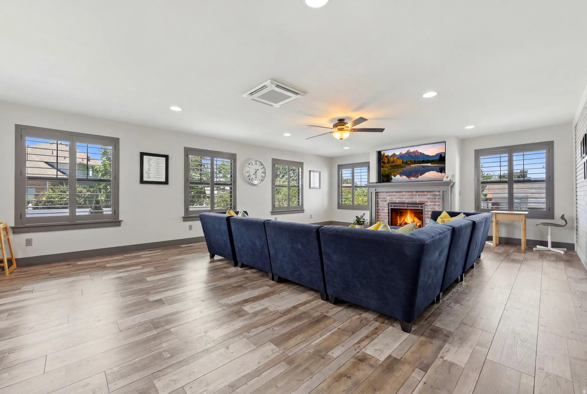 Spacious living area featuring wood-finish flooring, recessed lighting, and multiple windows with interior shutters