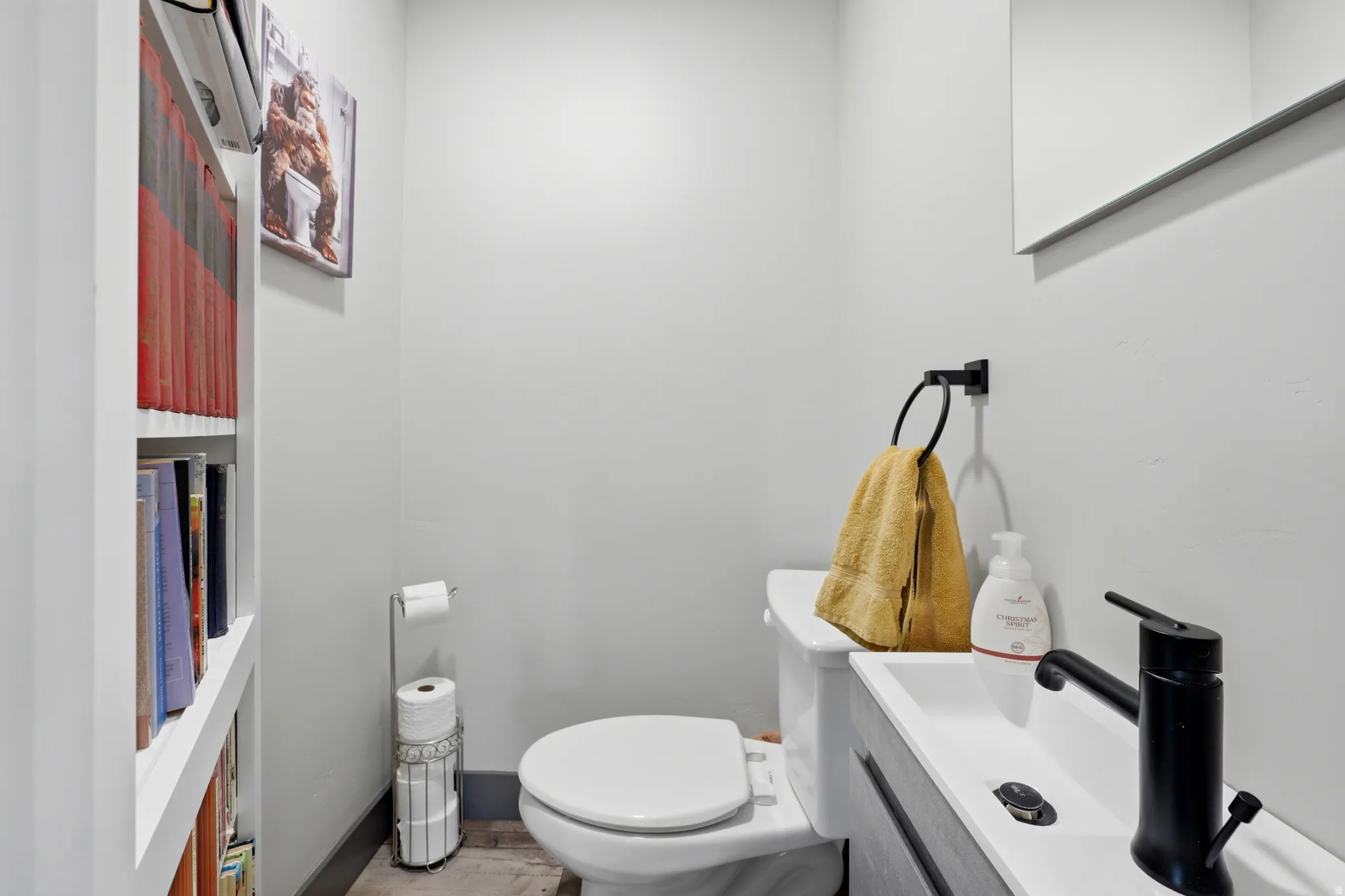 Compact powder room featuring a wall-mounted sink with a matte black faucet, a white toilet, and light gray walls
