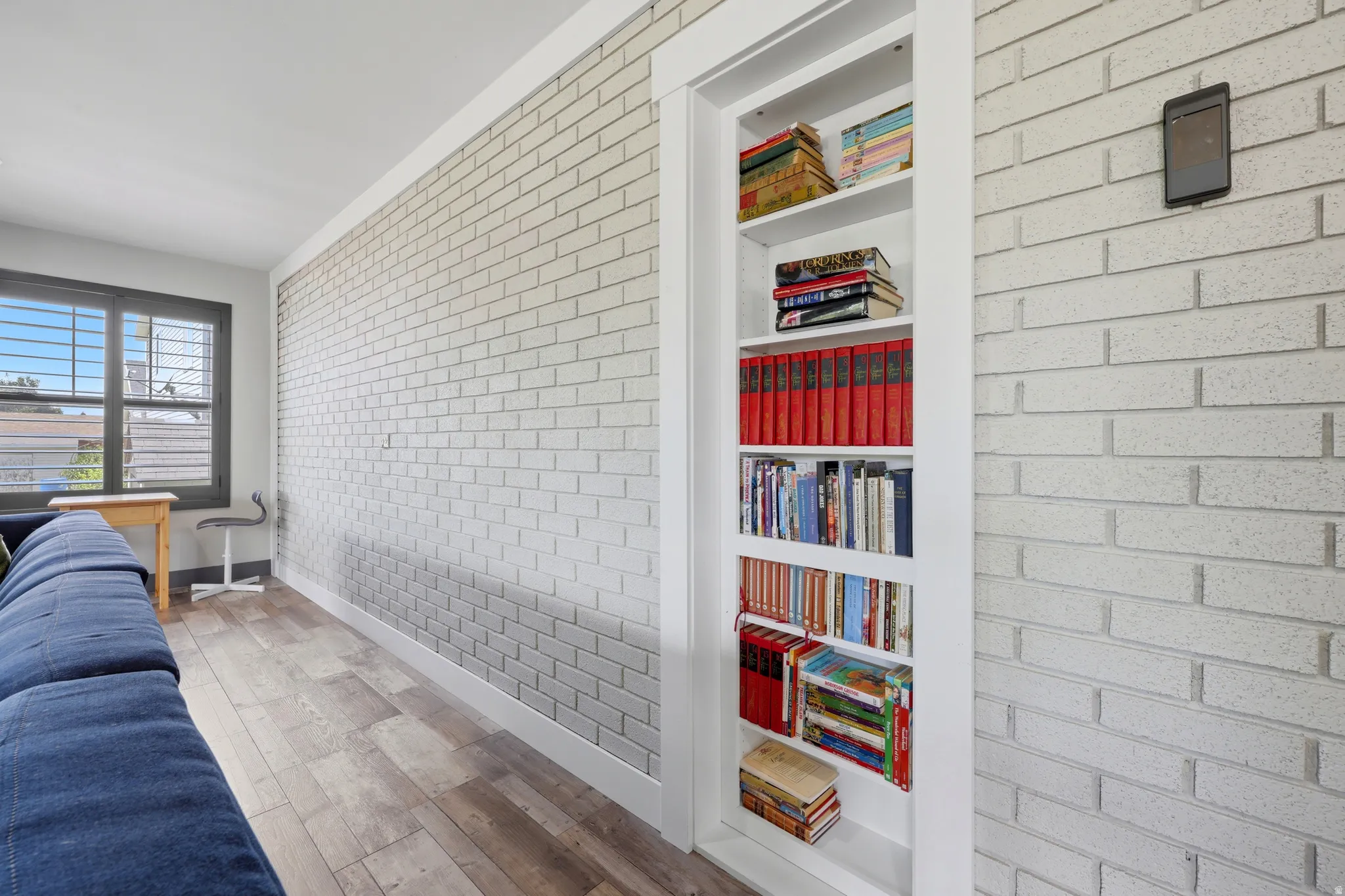 Built-in shelving with white trim and a concealed door, complemented by light-toned brick-patterned walls