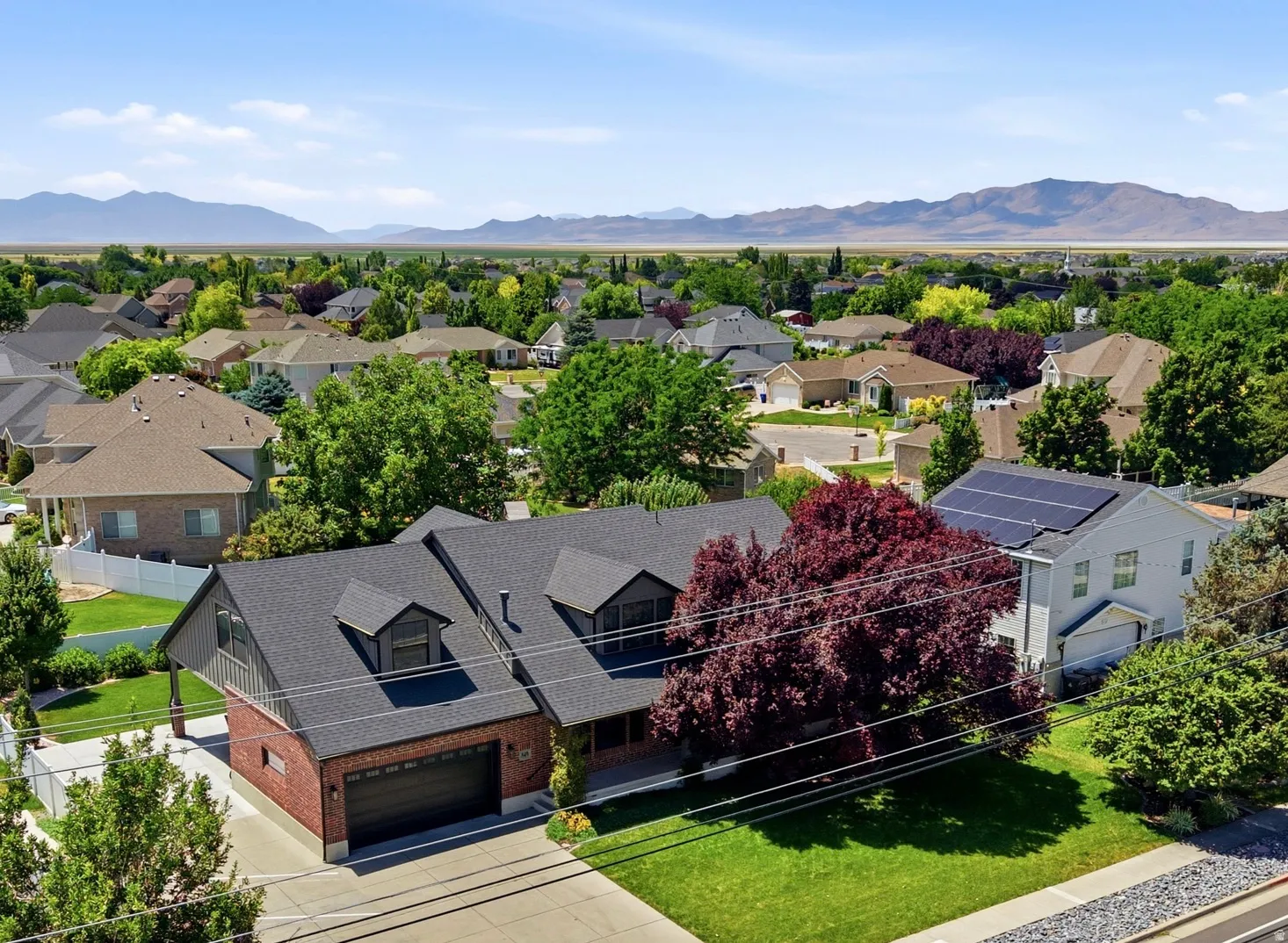 Brick and siding exterior with a dark shingle roof featuring multiple dormers