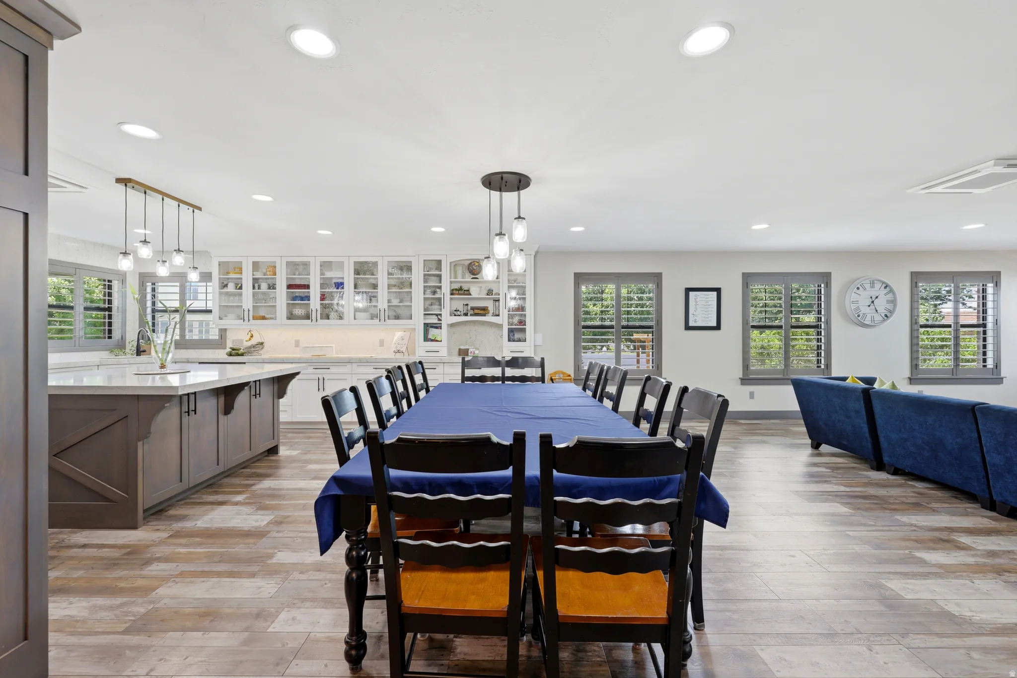 Open-concept kitchen and dining area featuring wood-finish flooring, recessed lighting, and multiple windows with plantation shutters