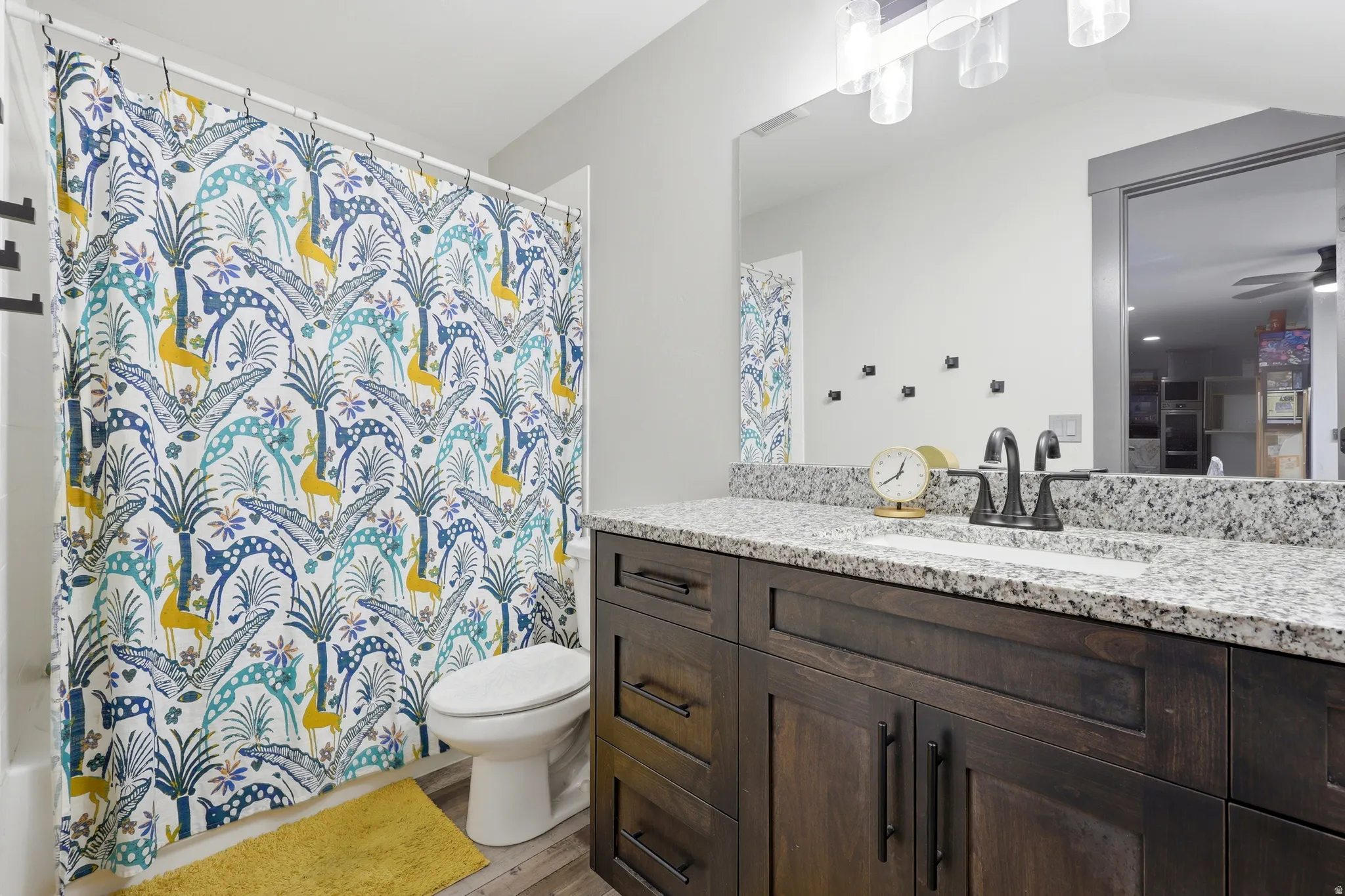 Bathroom vanity featuring a granite countertop, undermount sink, and dark wood-finish cabinetry