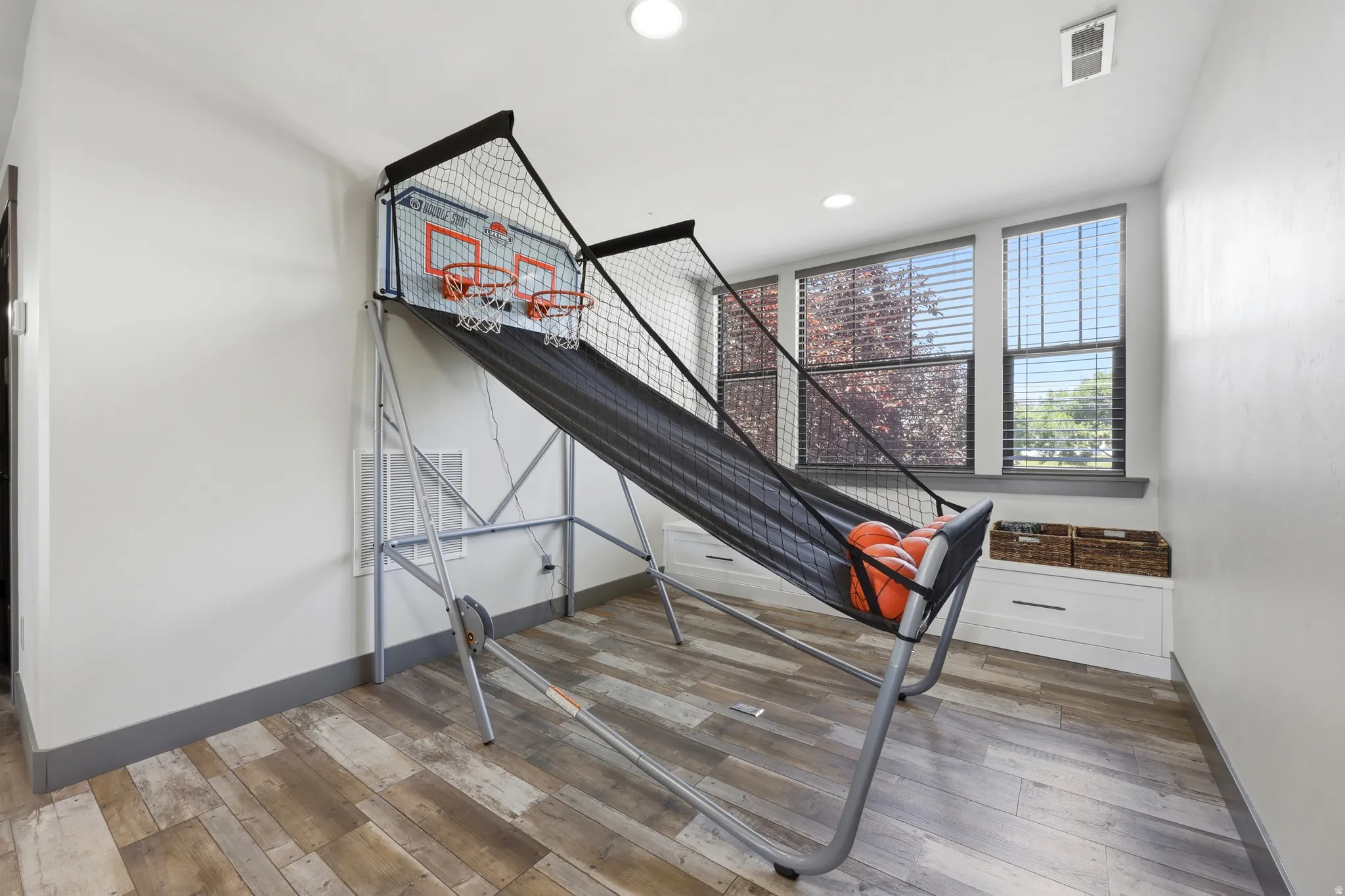 Spacious room featuring wood-finish flooring, white walls, and recessed lighting