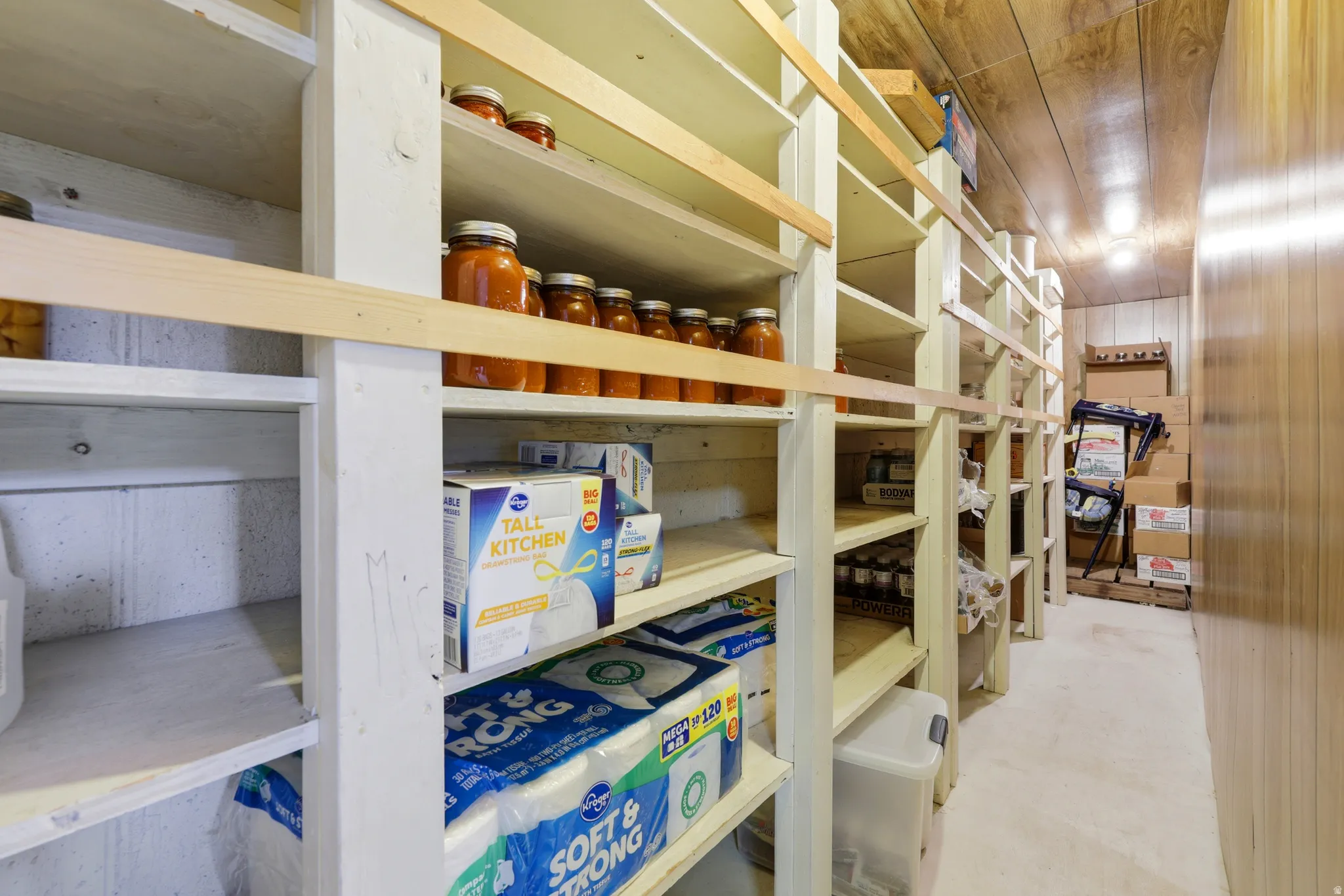 Dedicated pantry room featuring extensive built-in shelving, wood-finish wall panels, and a wood-finish ceiling