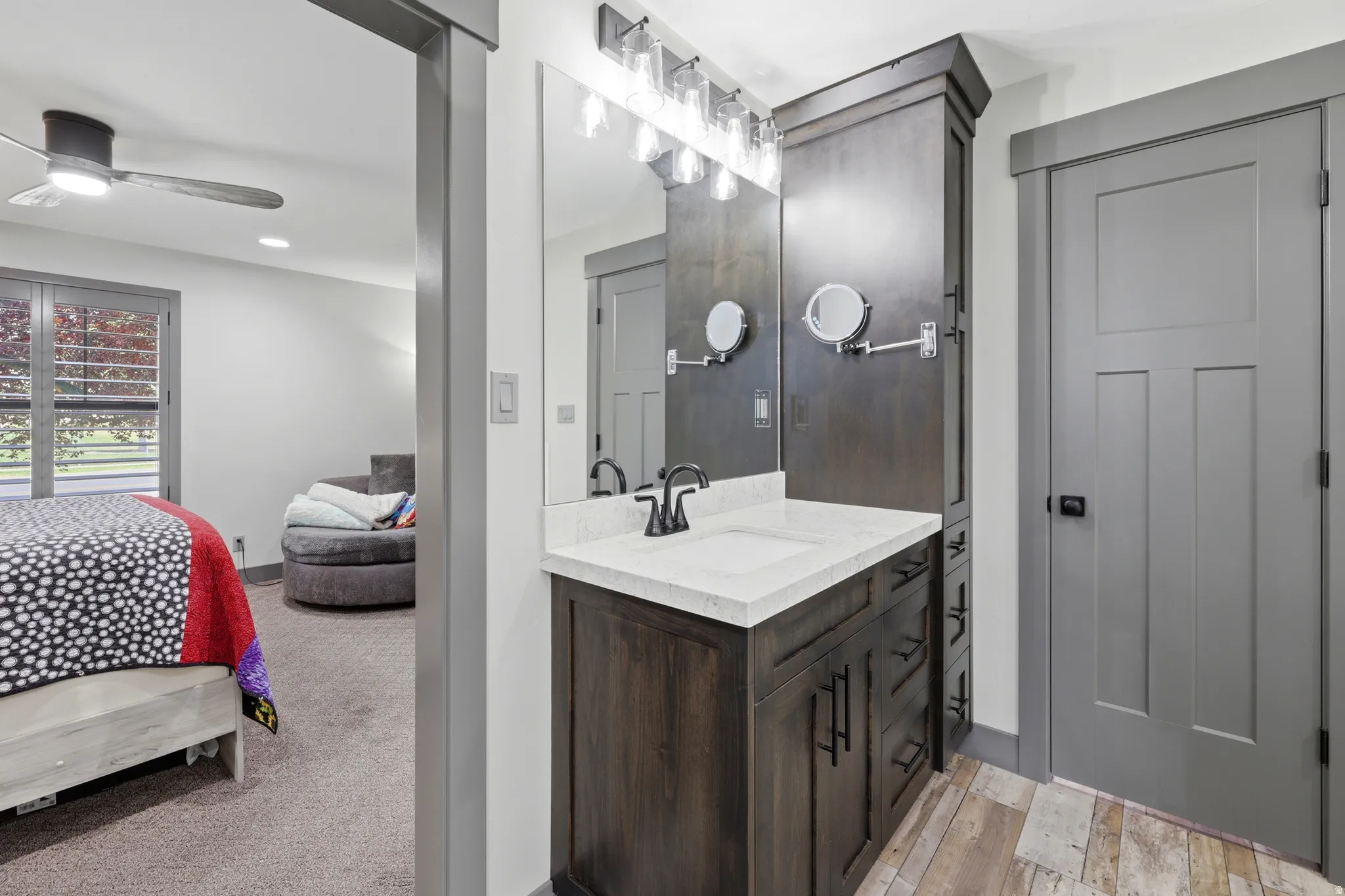 Vanity area featuring a dark wood-finish cabinet with white countertop, undermount sink, and matte black faucet