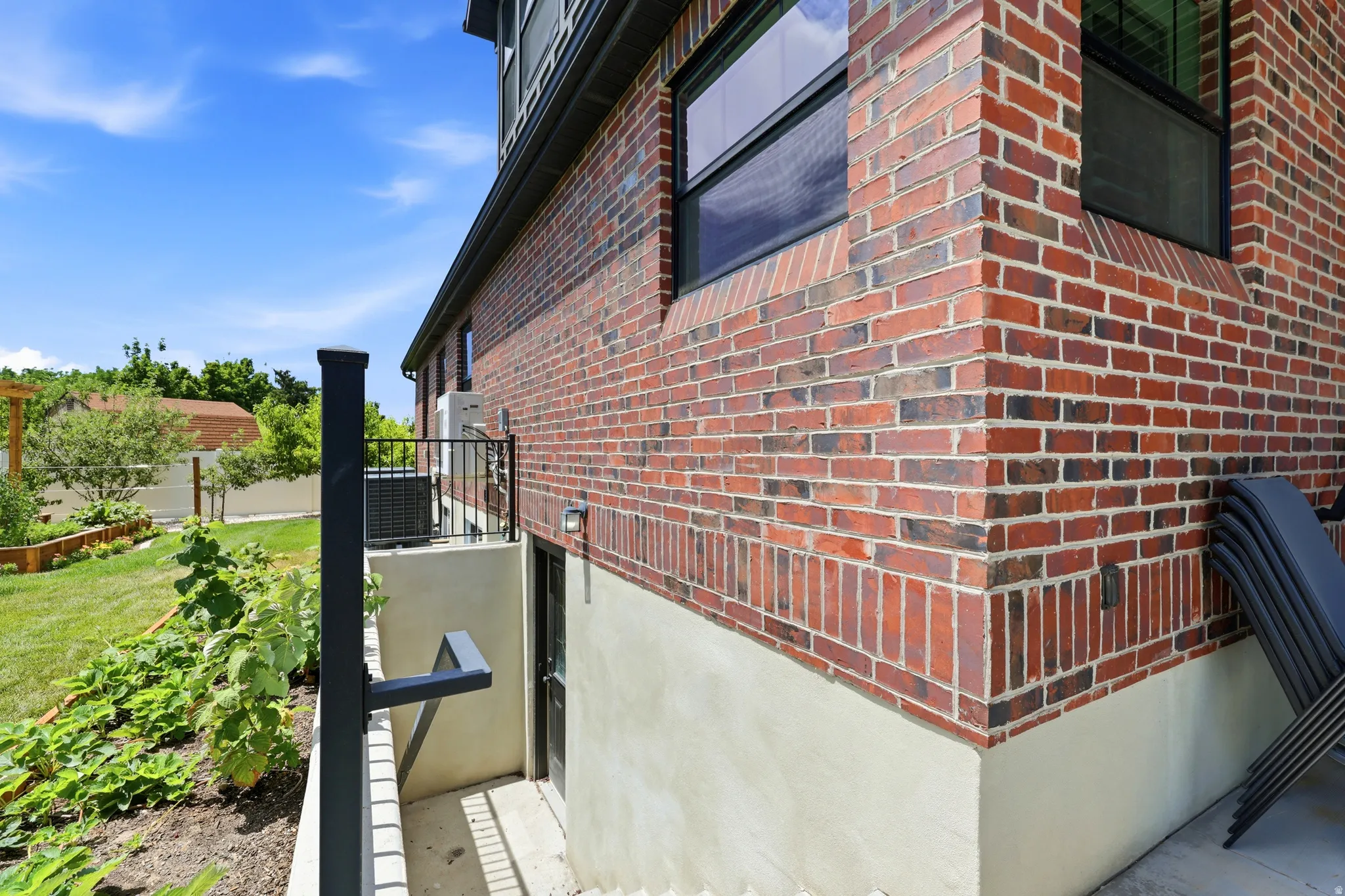 Brick exterior with a light-colored foundation, featuring black-framed windows and a dedicated entry point