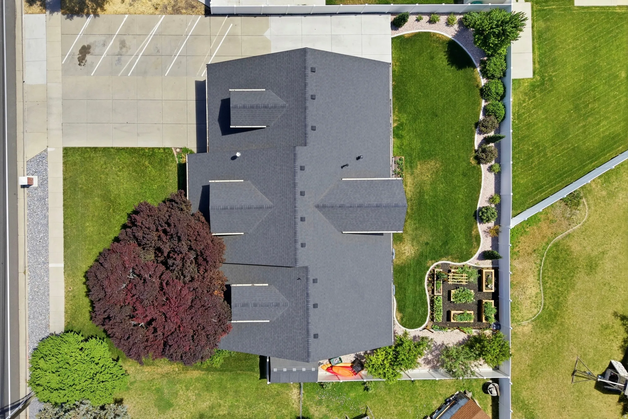 Property featuring a shingle roof, established landscaping, and a well-defined garden area with raised beds