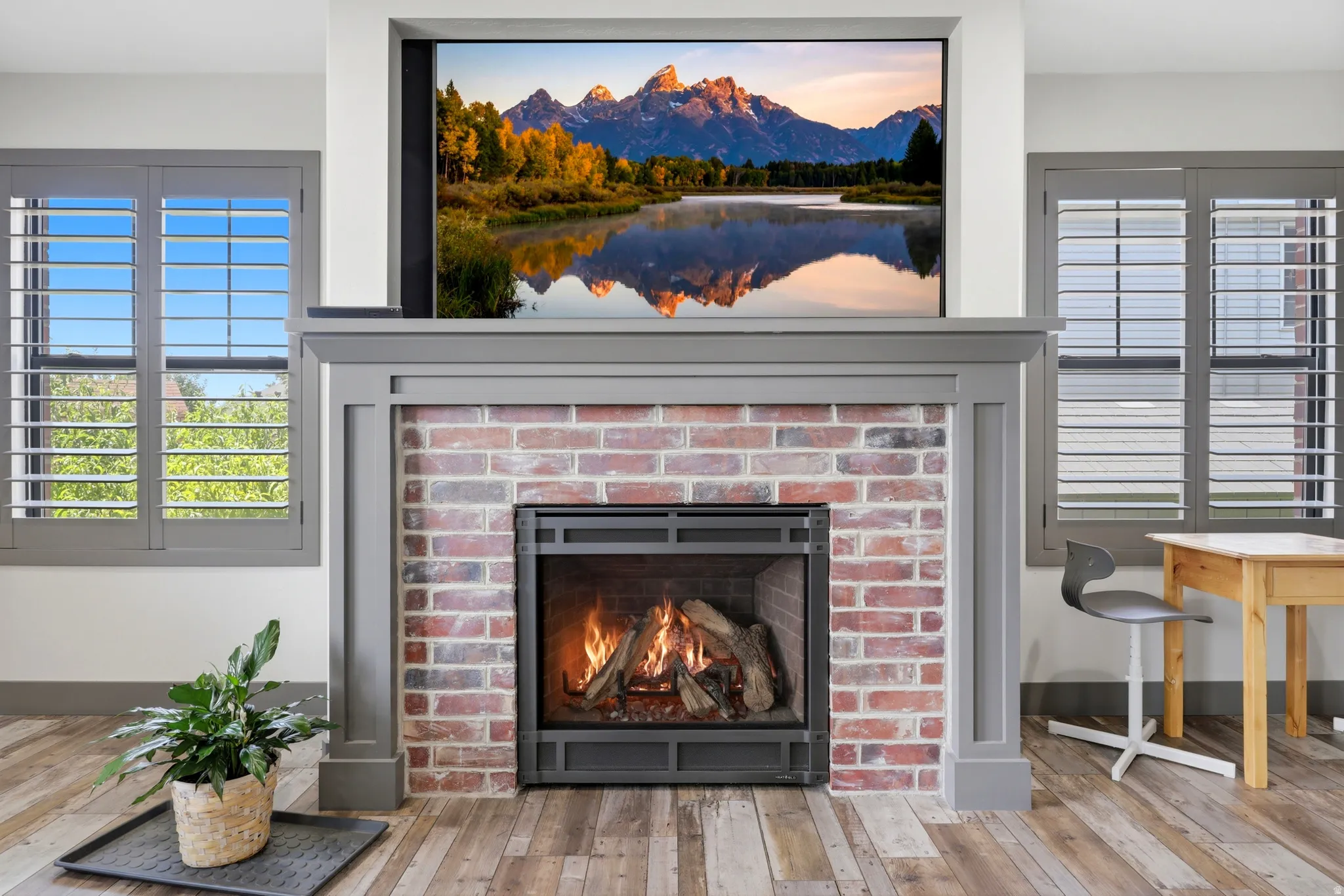 Integrated fireplace with a painted wood mantel, brick surround, and flush-mounted television above