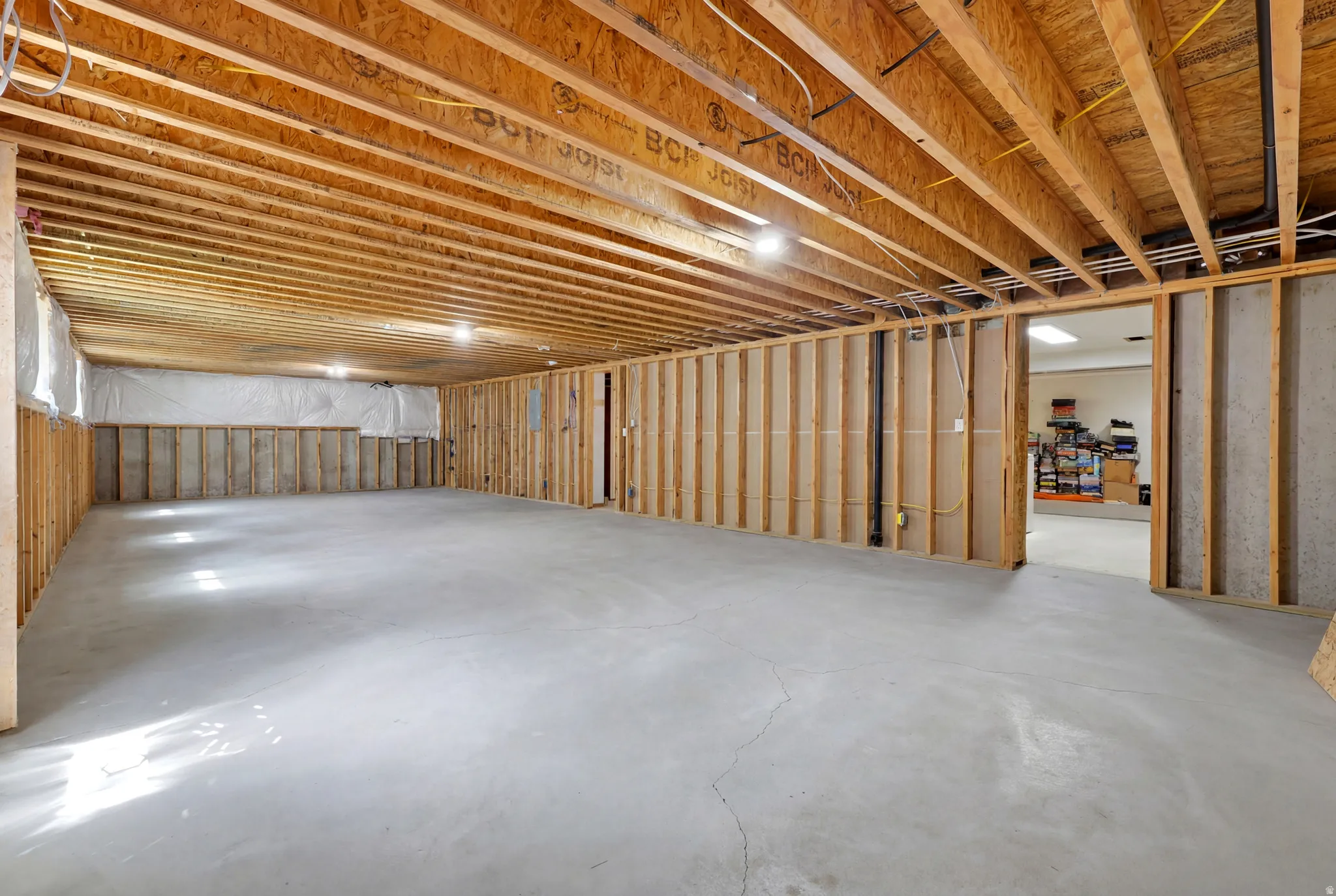Unfinished basement with exposed wood joists and concrete flooring