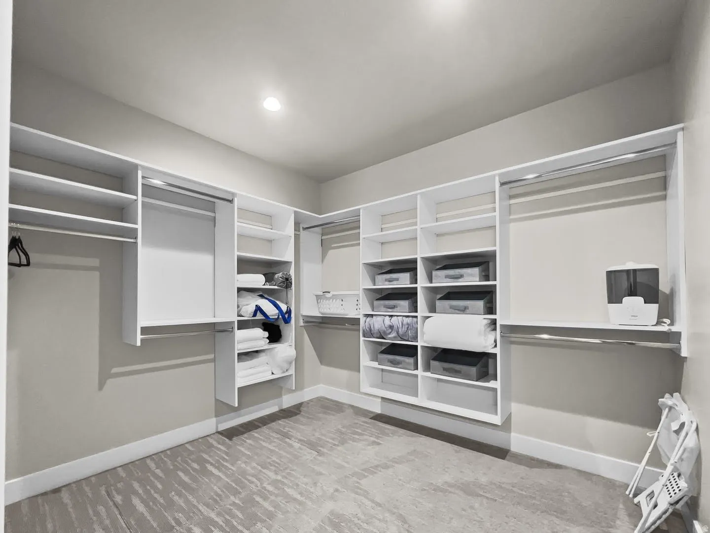 Custom walk-in closet featuring built-in white shelving, multiple hanging rods, recessed lighting, and a patterned carpet