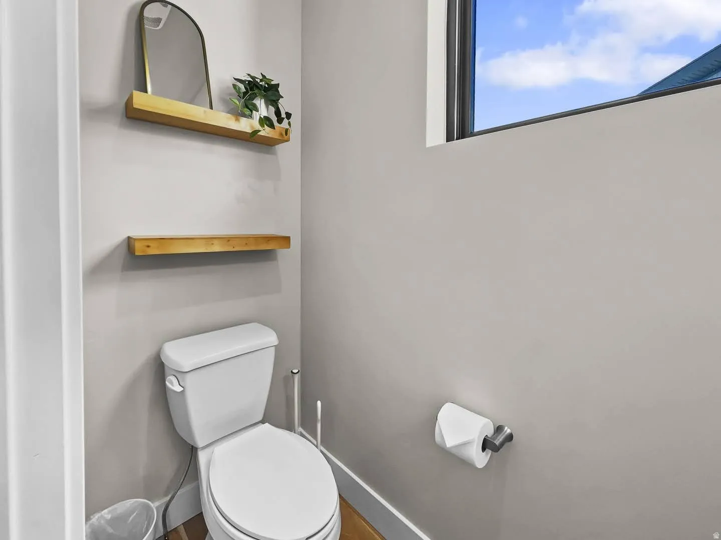 Powder room with a white toilet, light gray walls, and a high window