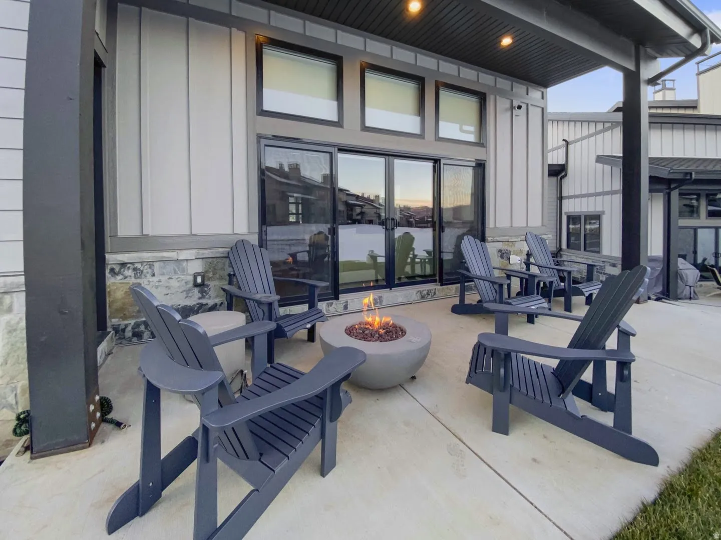 Covered patio featuring a concrete fire pit, concrete flooring, and a board and batten siding exterior with stone accents