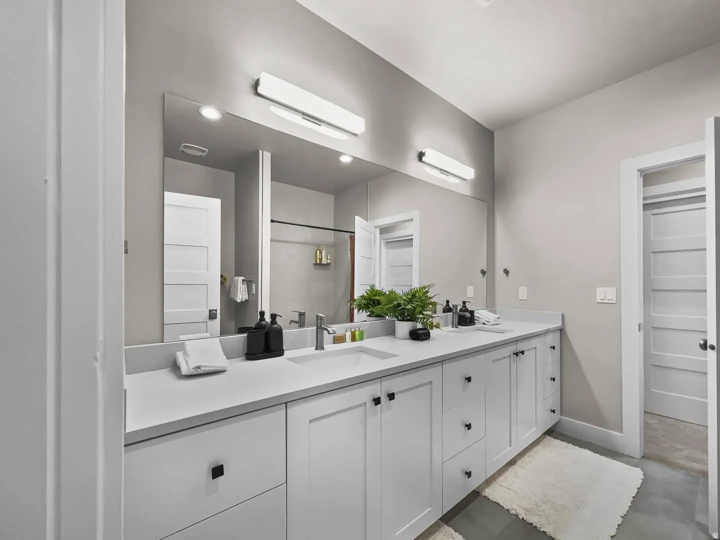 Expansive bathroom featuring a double vanity with ample counter space, dual sinks with chrome faucets, and extensive under-cabinet storage