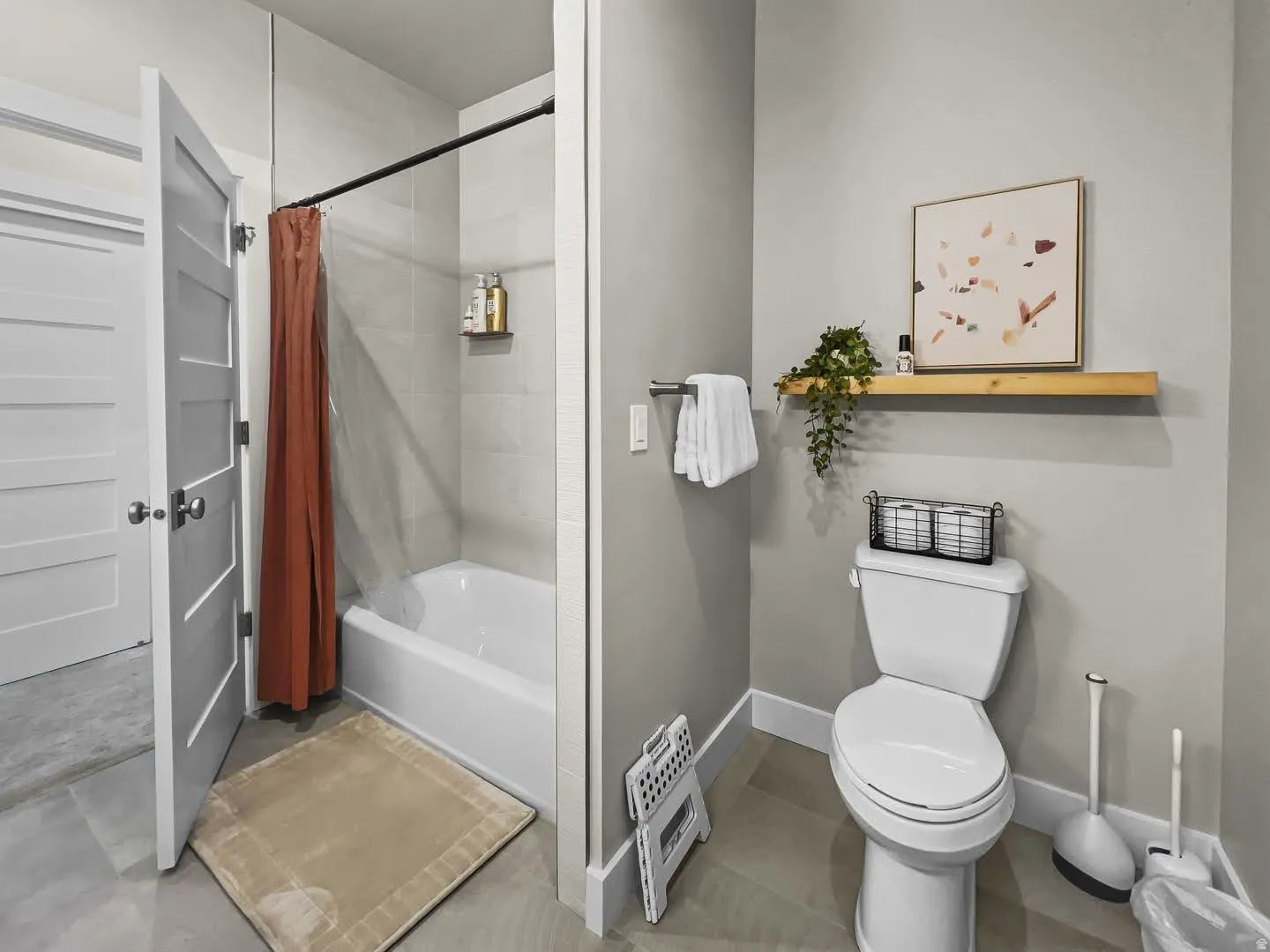 Bathroom featuring a white tub with light gray tile surround, a white toilet, and light gray wall paint