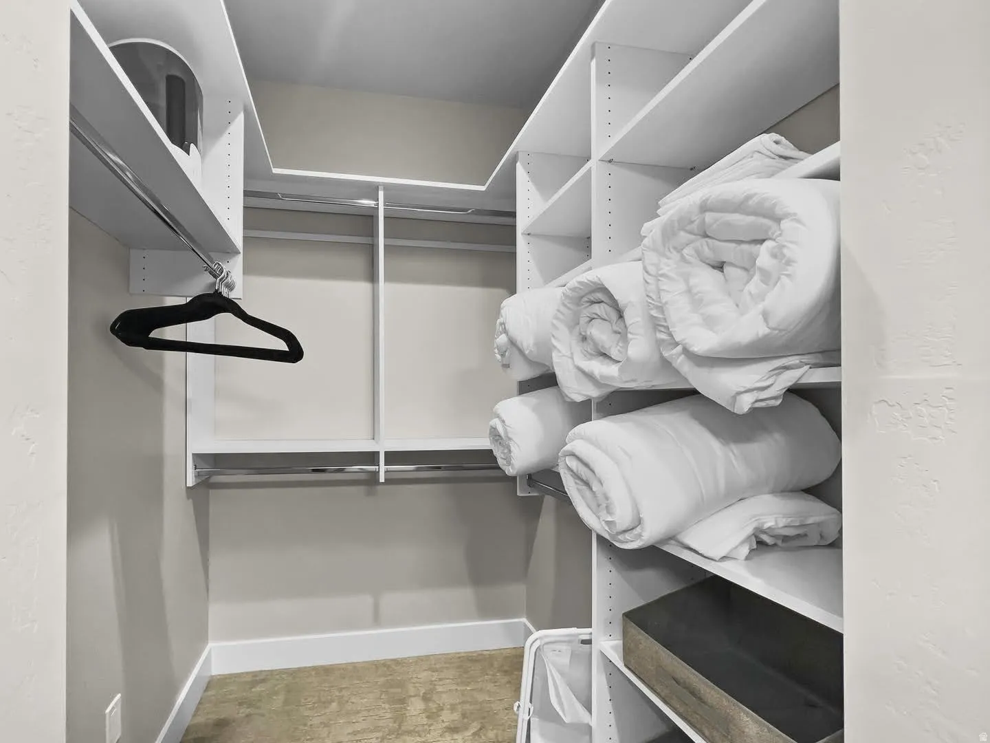 Walk-in closet featuring white built-in shelving, multiple hanging rods, and light-toned wall paint