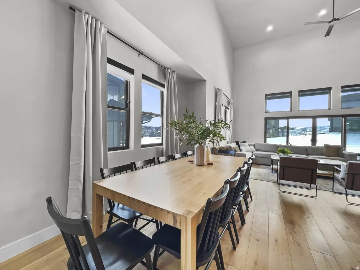 Open-concept living space featuring high vaulted ceilings, light wood-finish flooring, and expansive windows