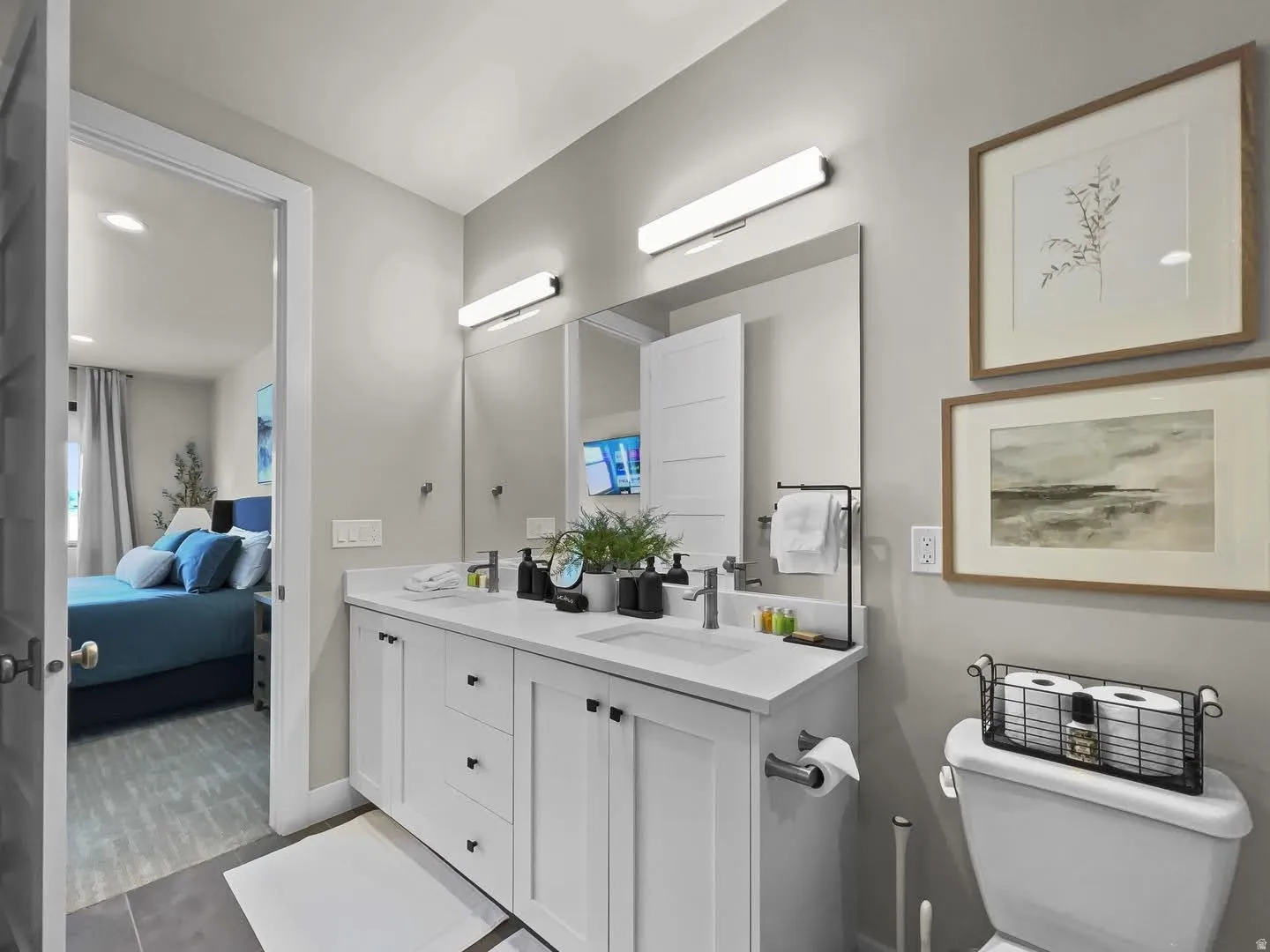 Bathroom featuring a double vanity with white cabinetry, integrated sinks, white countertops, and dual mirrors with horizontal lighting fixtures