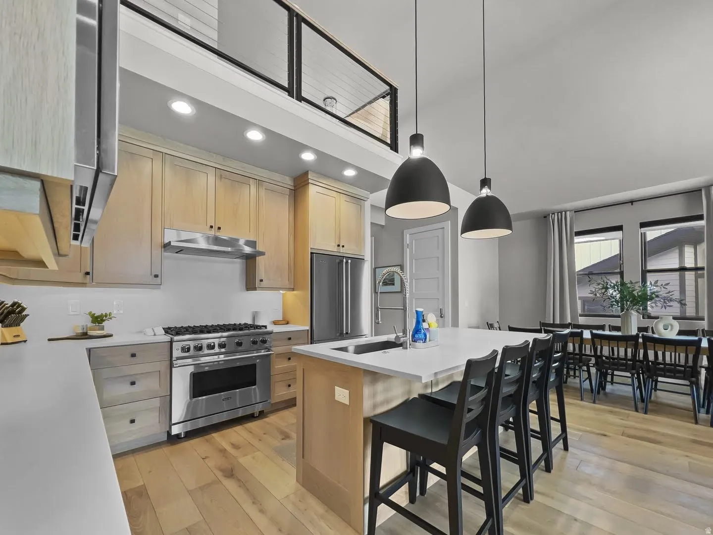 Open-concept kitchen with light wood-finish cabinetry, stainless steel appliances, and a central island featuring a white countertop