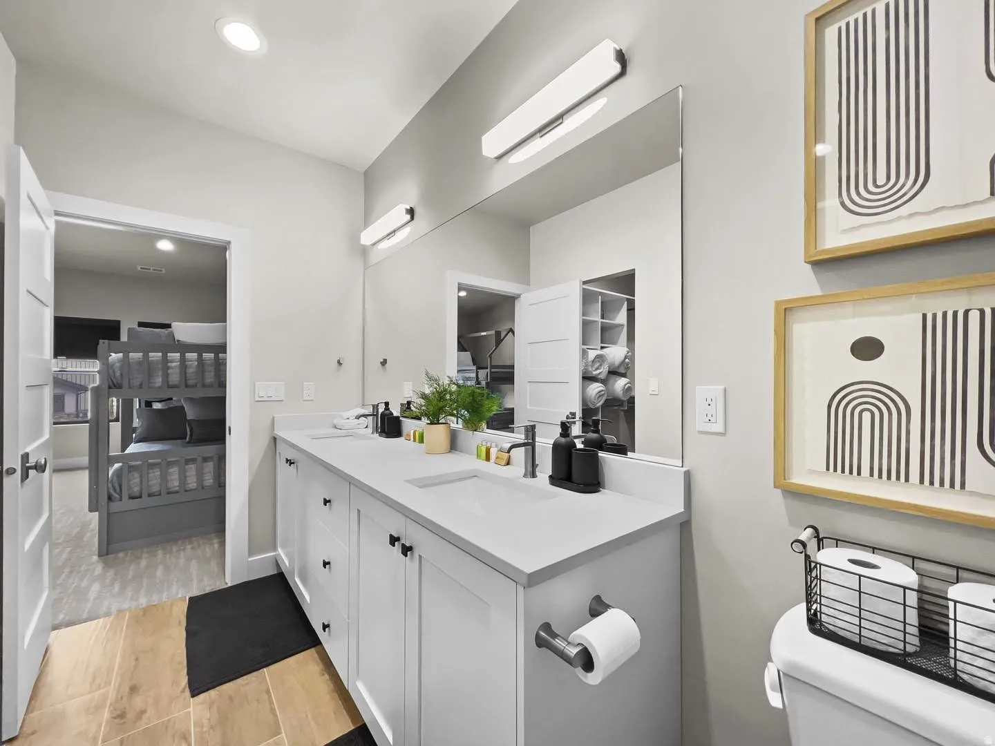 Double vanity featuring white cabinetry, undermount sinks, and a large mirror with integrated lighting