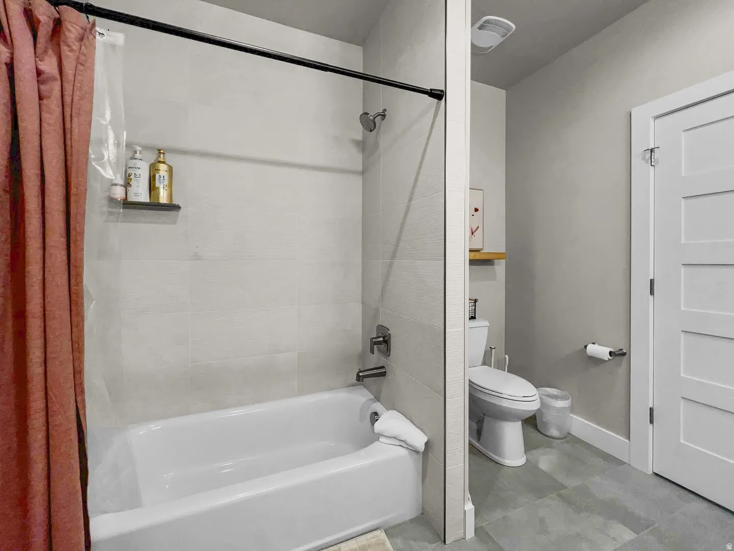 Bathroom featuring a tub and shower combination with light-toned tiled walls