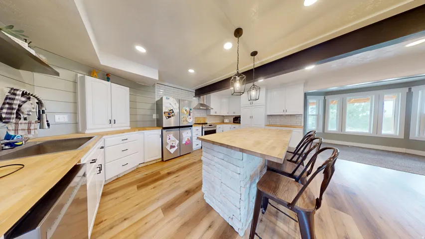 Kitchen featuring white cabinetry, light wood-finish countertops, stainless steel appliances, and wood-finish flooring