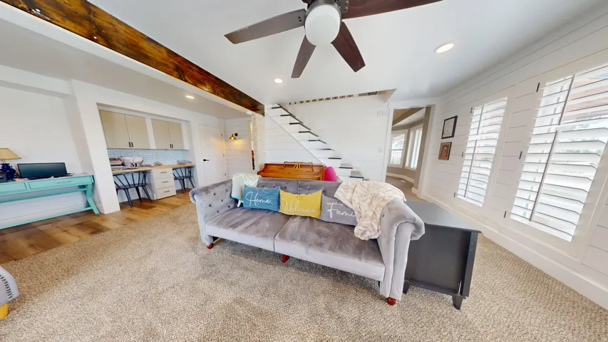 Spacious living area featuring a ceiling fan, recessed lighting, and wall-mounted sconce