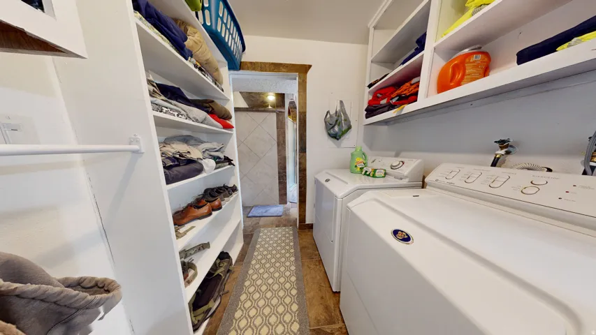 Dedicated laundry area featuring white appliances, built-in shelving, and wood-finish flooring