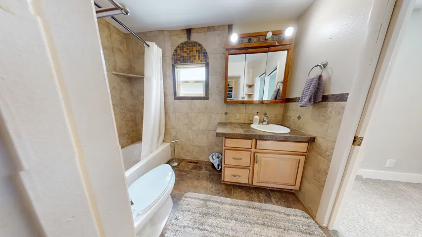 Bathroom featuring wood-finish vanity with countertop, integrated sink, and medicine cabinet