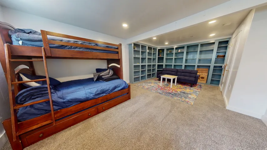 Spacious interior room featuring extensive built-in shelving, recessed lighting, wall-to-wall carpeting, and white baseboards
